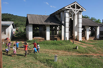 Children play a game on the farm at Africa University near one of the original buildings used when the school opened in 1992.