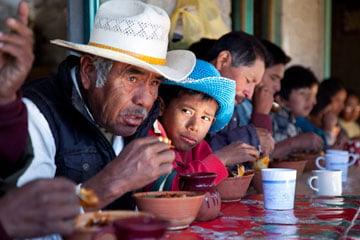 People of many ages share a community meal in San Miguel Huautla, Oaxaca, Mexico. Young people in rural areas of Mexico like this one often choose to emigrate to the United States and work for a few years because there are few opportunities at home.