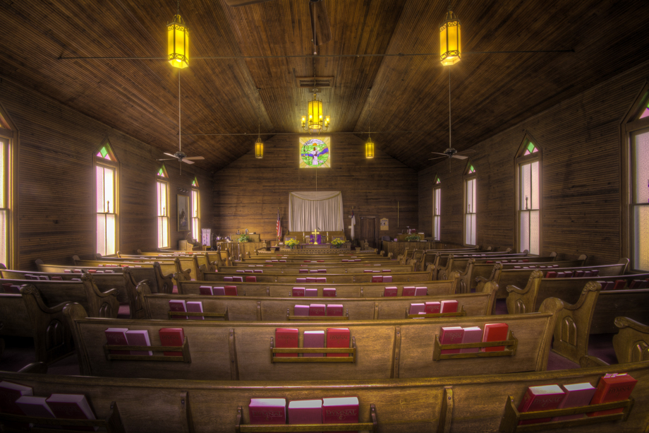 The interior of Dry Pond UMC includes wooden pews, horizontal wall and ceilings and warm yellow light from chandeliers. Photo by Scott MacInnis, courtesy Historic Rural Churches of Georgia.