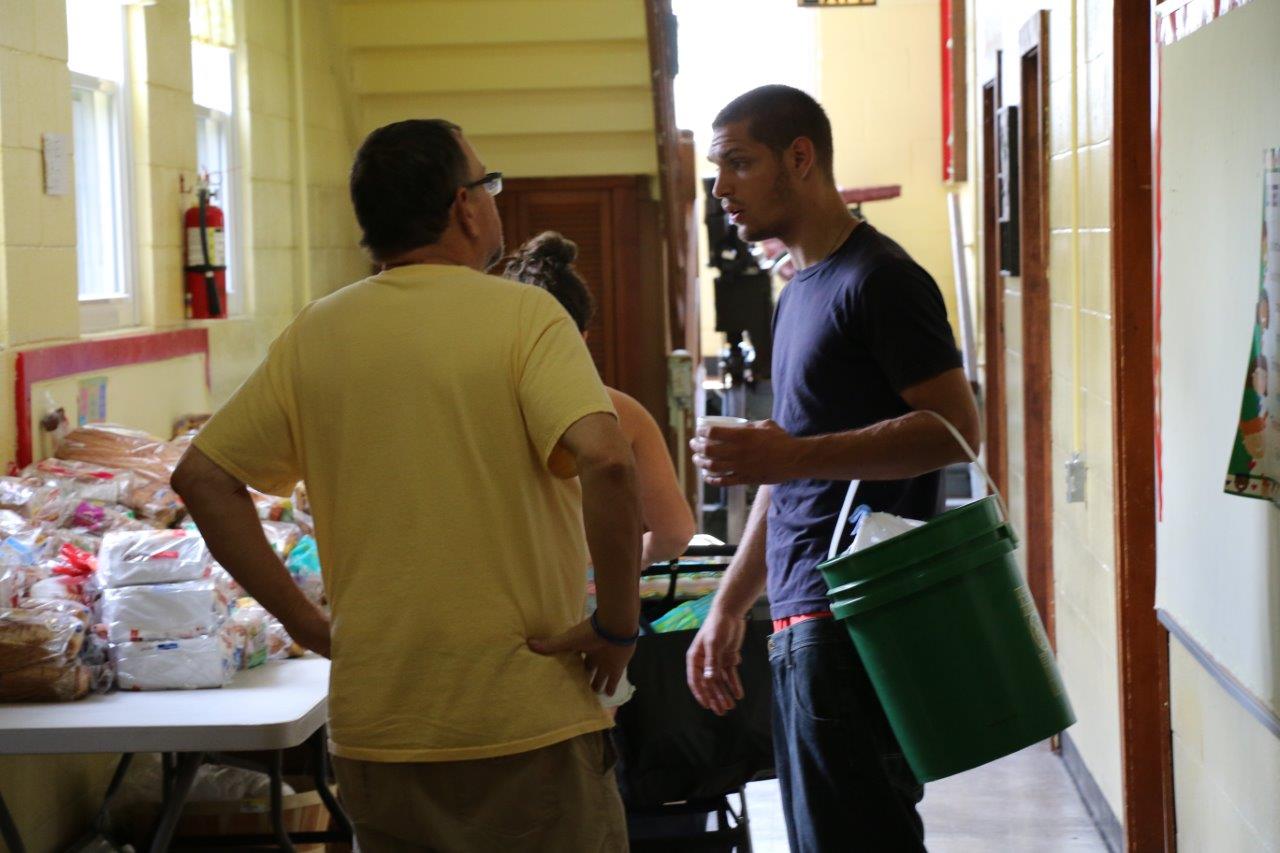 The Rev. Jeff Newton, left, pastor of Trinity United Methodist Church, helps a Kokomo family stock up on food and other supplies after the recent tornado that displaced many in the community. Photo by Skyler Nimmons