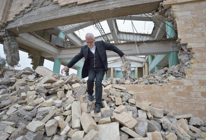 Father Emanuel Youkhana walks through the rubble of a church in Mosul, Iraq. The church belonged to the Ancient Church of the East. According to neighbors, the Islamic State group--which took over the city in 2014--used the building as a warehouse until the final weeks of their occupation, when they awarded the building to a contractor who began to demolish it in order to salvage the steel rebar in the walls. Although this portion of the city was liberated in early 2017, Christians are unlikely to return soon due to concerns about their security in the Sunni community. Photo © Paul Jeffrey.