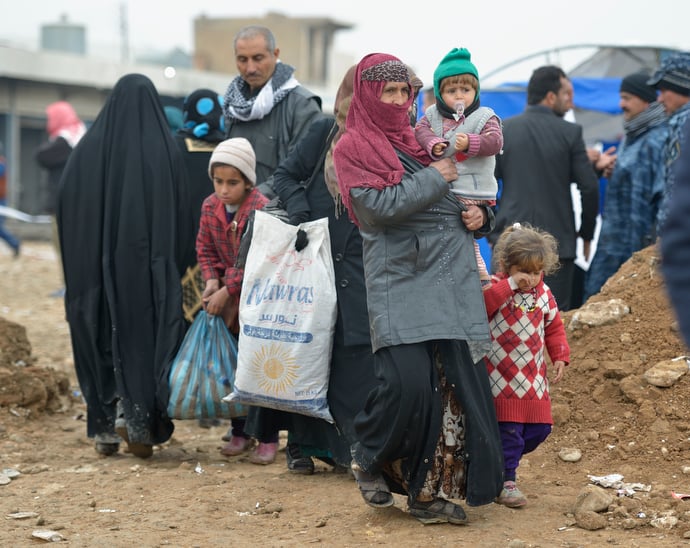 Displaced by fighting between the Iraqi army and the Islamic State group, a family leaves a processing center for displaced families outside Mosul, Iraq. Although the eastern portion of the city has been liberated from ISIS, fierce fighting is predicted as the army moves to retake the remainder of the city. Photo © Paul Jeffrey.