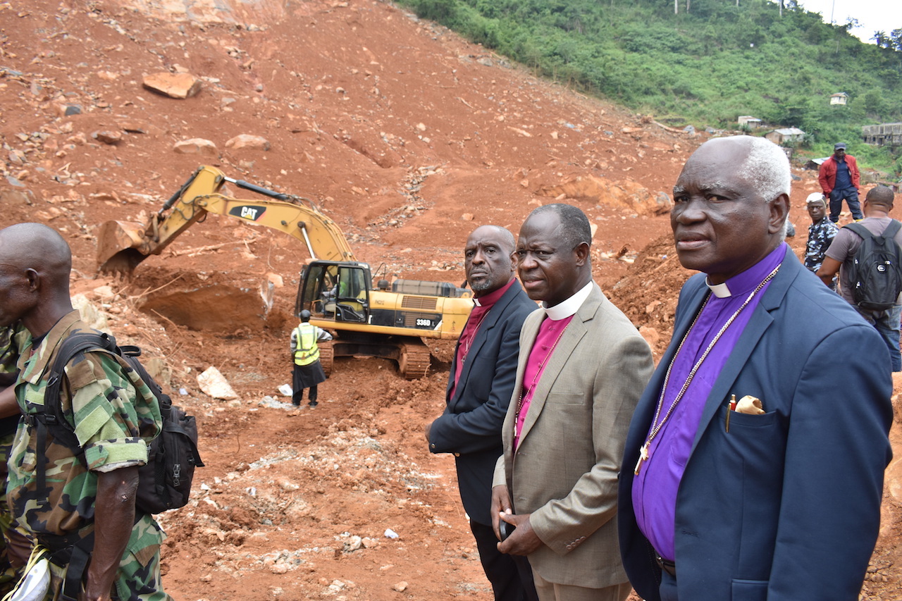 United Methodist Bishop John Yambasu (center, at right) joins with other clergy from the Council of Churches in Sierra Leone to visit two communities hit by flooding and a mudslide near Freetown, Sierra Leone. “The amount of homes that were buried in that rubble ... to know that I was really standing on top of human beings crushed by the landslide was most devastating for me,” he said.” Photo by Phileas Jusu, UMNS.