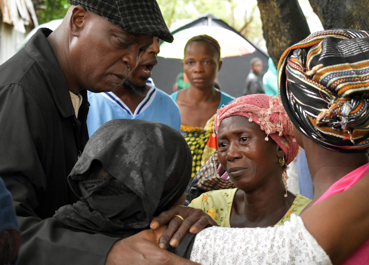 The Rev. Henry Samuel of Vine Memorial Baptist Church, an affiliate member of the Council of Churches in Sierra Leone, prays with and consoles a group of women who lost 17 members of their family during the Aug. 14 flood and landslide in in Freetown. Photo by Phileas Jusu, UMNS.