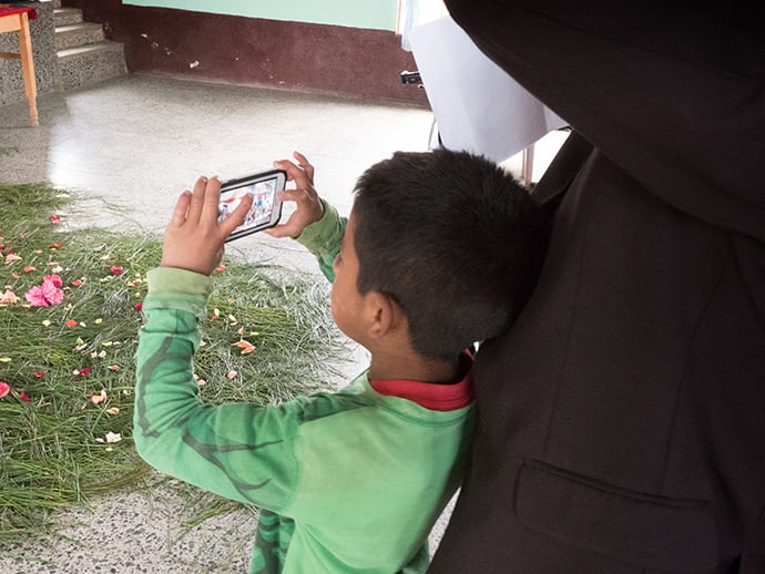 A young member of Iglesia Nacional Methodista Primitiva Fuente De Vida, joins in as one of the photographers during a visit from U.S. United Methodist bishops and church leaders.