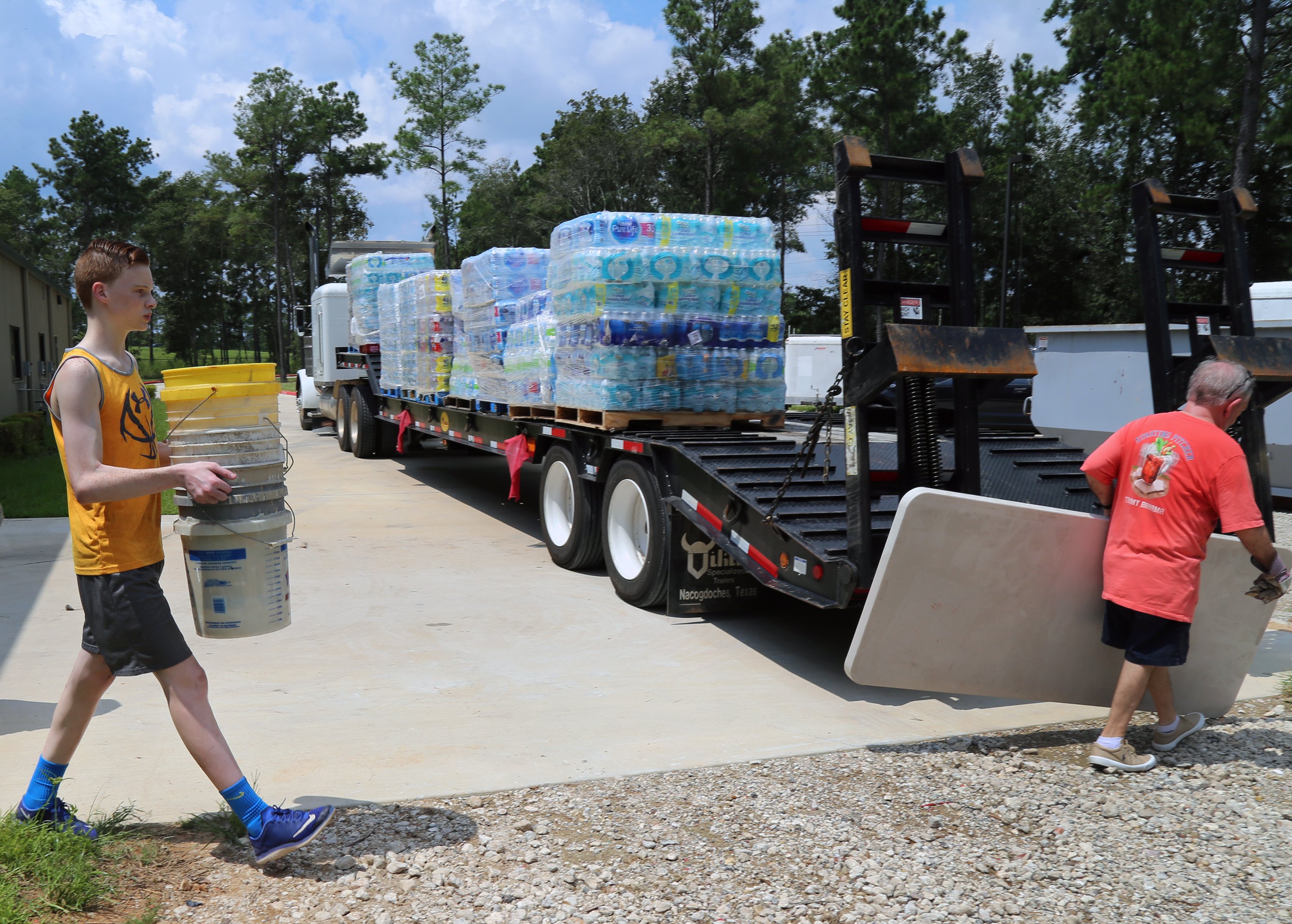 Volunteers carry a bucket and a table during efforts by the Texas Conference to help provide water for Hurricane Harvey relief teams in Beaumont, Texas, after floodwaters shut down the town’s water system. Photo by Sydney Mares, courtesy of the Texas Conference.