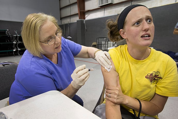 Krissah Dickerson grimaces after receiving a tetanus shot by nurse Ruth Hasson inside the gym at First United Methodist Church in Vidor, Texas. Photo by Kathleen Barry, UMNS.