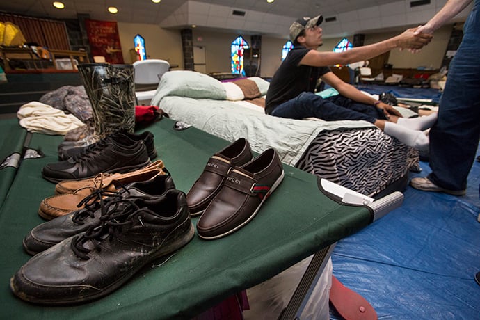 The gym at Woodcrest United Methodist Church in Lumberton, Texas, serves as a shelter to many including Stevon Ford (on cot) who is shaking the hand of Allen Smith. Smith, who was helping to run the shelter, has given Ford a job. Photo by Kathleen Barry, UMNS.