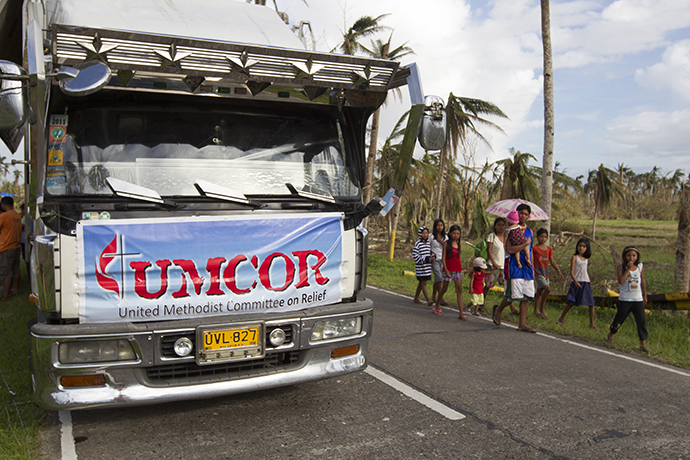 Community members walk past a food distribution site for the United Methodist Committee on Relief following Typhoon Haiyan in Dagami, Philippines, in 2013. Photo by Mike DuBose, UMNS.  