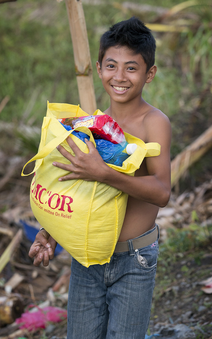 A young boy leaves a food distribution center set up by the United Methodist Committee on Relief carrying food for his family following Typhoon Haiyan in Dagami, Philippines, in 2013. Photo by Mike DuBose, UMNS.