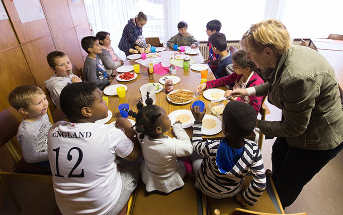 Volunteer Hannah Guzinski helps serve a meal to immigrant children in an art education  enrichment program at the United Methodist Peace Church in Hamburg, Germany. A number of United Methodist congregations in Germany are assisting refugees. Photo by Mike DuBose, UMNS.