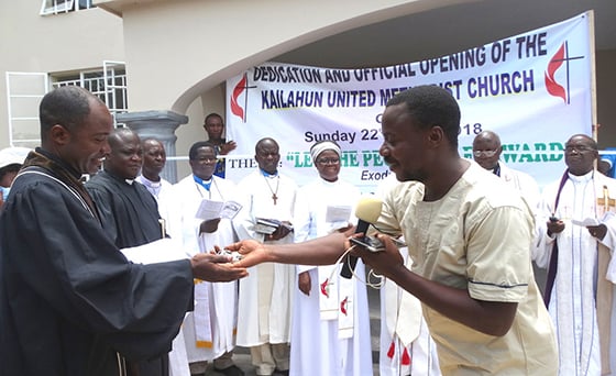 A building engineer (right) hands over the keys of Grace United Methodist Church to the Rev. Samuel Kailie, pastor in charge of the new church in Kailahun, Sierra Leone, during a dedication ceremony in April. Photo by Phileas Jusu, UMNS .