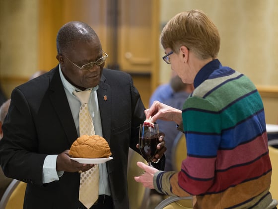 Bishop José Quipungo of the East Angola Area (left) and Sue Laurie of Love Prevails, an unofficial group that advocates for the full inclusion of LGBTQ individuals in all aspects of church life, share Holy Communion during the United Methodist Council of Bishops meeting in Chicago. Photo by Mike DuBose, UMNS.