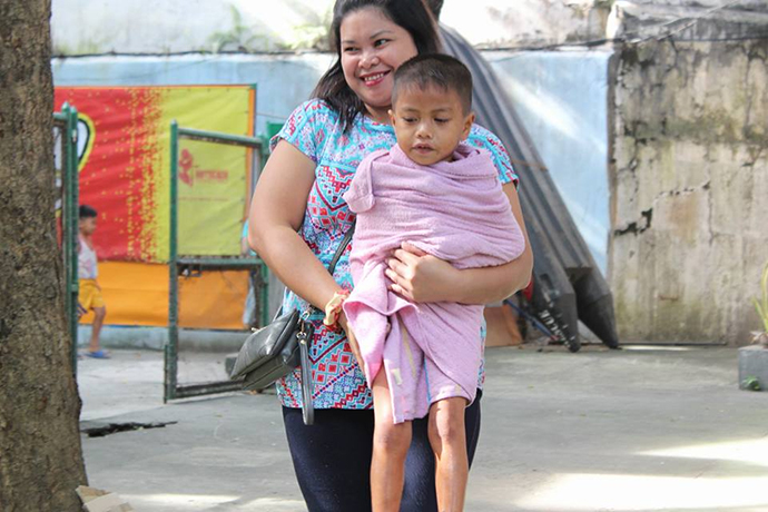 A volunteer carries a child after his bath at Central United Methodist Church in Manila, Philippines. During the church’s Ligo Land ministry, volunteers help bathe about 40 children each week. The kids get new clothes and enjoy snacks and stories in the church. Photo courtesy of Aquilino Javier.