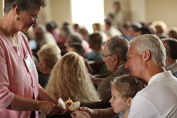 The Rev. Dorothy Ann Webster (left) lights candles during the first worship service at Ford's Chapel United Methodist Church in Harvest, Ala., after a tornado damaged the sanctuary in April 2011. A UMNS file photo by Kathleen Barry.