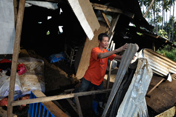 Armando Guniyon pulls apart the rubble of his home, damaged by floodwaters from Typhoon Bopha, in Cagayan de Oro, Mindanao, Philippines.