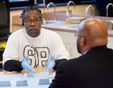 Brett Harleston (left), a community liaison, explains the HIV antibody test to Ross Fleming III, a member of the Meharry staff. A UMNS photo by Mike DuBose.