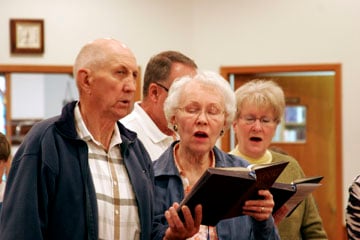 Robert and Faye Sundin praise God at Bowbells United Methodist Church. Behind them are Dean and Sally Verstrate. A UMNS photo by Jan Snider.