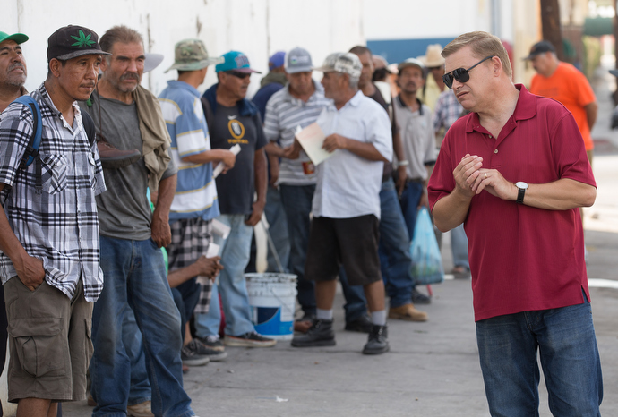 The Rev. Jacob Van Der Schaaf (center) and Elly Rodiles (right) from La Santísima Trinidad Methodist Church offers breakfast and a prayer to Jesus Perez in Mexicali. Photo by Mike DuBose, UMNS.