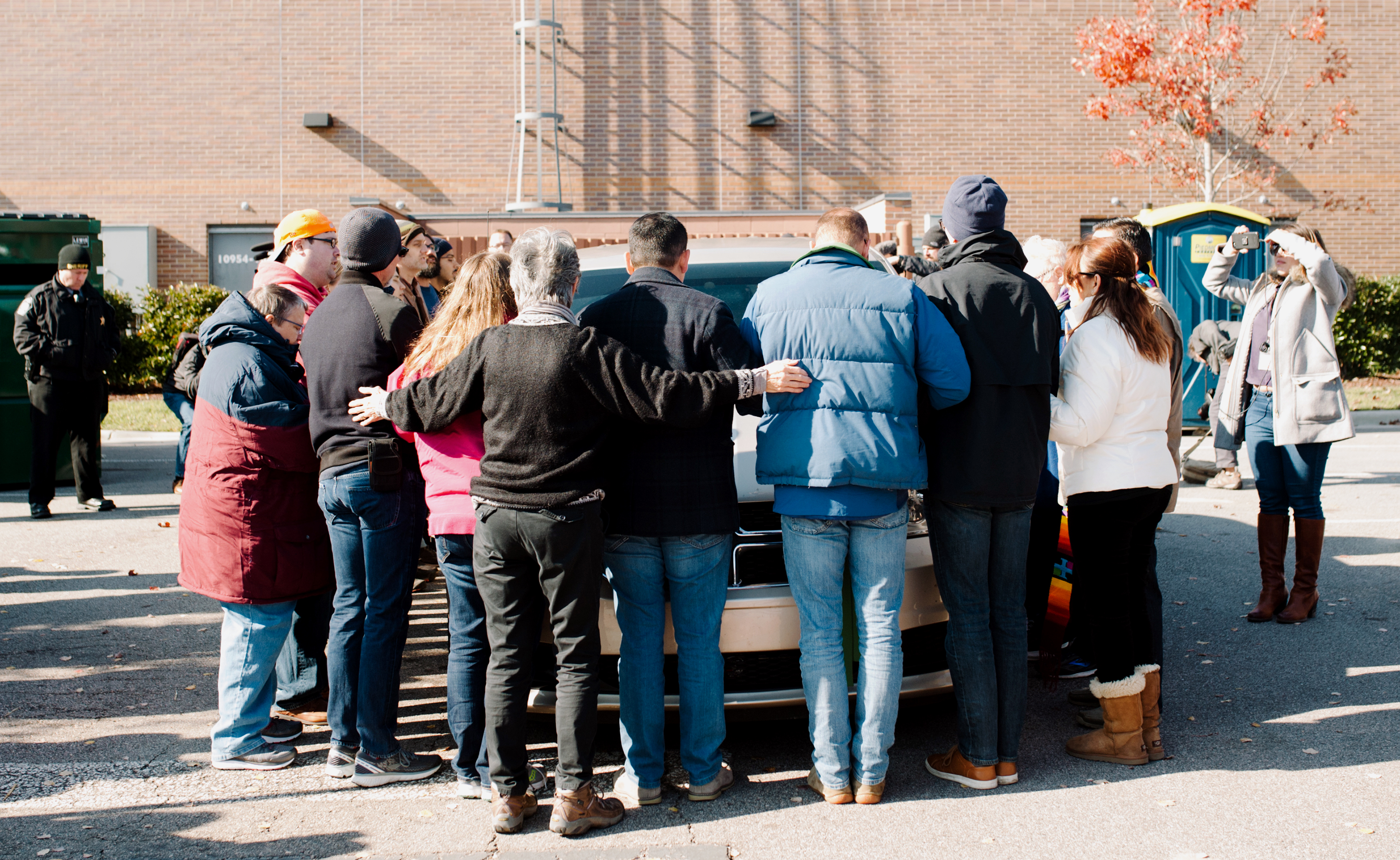 Faith leaders and church members surround a government vehicle after Samuel Oliver-Bruno was arrested on Nov. 23 by ICE officials. Oliver-Bruno had left CityWell United Methodist Church to meet with U.S. Citizenship and Immigration Services in Morrisville, N.C., for an appointment. Photo by Anna Carson Dewitt, courtesy of CityWell United Methodist Church.