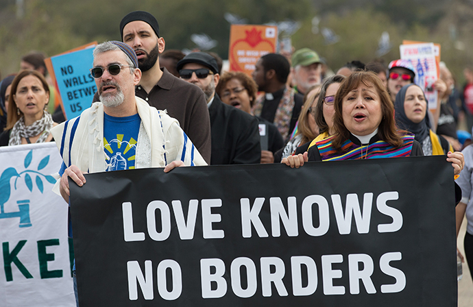 United Methodist Bishop Minerva Carcaño (right) and Rabbi Brant Rosen help lead a multifaith march in support of justice for migrants at Border Field State Park In San Diego. Photo by Mike DuBose, UMNS.