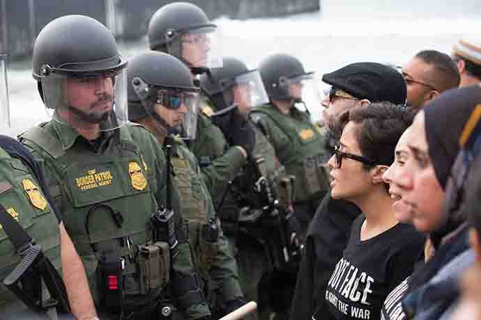 Faith leaders and other supporters of immigrant rights face U.S. Border Patrol agents at the fence between the U.S. and Mexico in San Diego as they attempt to offer a ceremonial blessing in support of migrants seeking refuge in the U.S. Photo by Mike DuBose, UMNS.