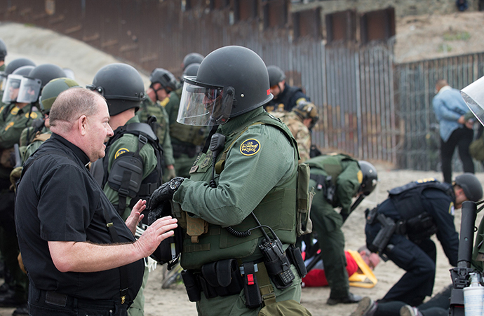 The Rev. Rolly Loomis, pastor of First United Methodist Church of Roseville, Calif., is detained by a U.S. Border Patrol agent at the fence between the U.S. and Mexico in San Diego. Loomis joined with other faith leaders in attempting to offer a ceremonial blessing in support of migrants seeking refuge in the U.S. Photo by Mike DuBose, UMNS.