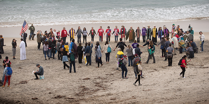 Faith leaders and supporters of immigrant rights gather in prayer on the beach near the U.S. Mexico border in support of migrants seeking refuge in the U.S. Photo by Mike DuBose, UMNS.