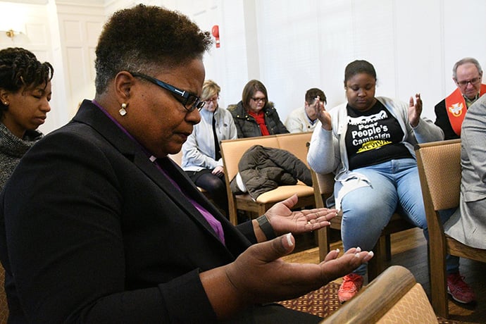 Bishop LaTrelle Easterling prays with others inside the United Methodist Building before delivering a statement on the government shutdown on the front steps of the United Methodist Building. Photo by Melissa Lauber, Baltimore-Washington Conference. 