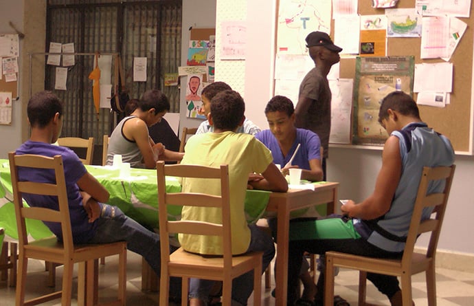 Guests sit at a table in the House of Cultures, where refugees find temporary assistance and interact with the local community. Photo courtesy of Mediterranean Hope.