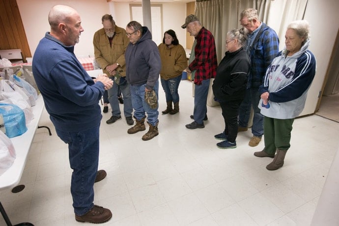 The Rev. Harold George (left) prays with community members during a food distribution at Oak Grove United Methodist Church in Fisher, W.Va. George also serves as an emergency first responder, which puts him in the front lines of the opioid crisis. “You pray on the way to calls, you pray your way through calls, you pray for the people after the calls,” he said. Photo by Mike DuBose, UMNS.