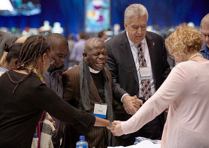 Delegates pray together during the Feb. 23, 2019, opening session of the Special Session of the General Conference of The United Methodist Church. In the center is the Rev. Jerry Kulah a supporter of the Traditional Plan from Liberia. Photo by Paul Jeffrey, UMNS. 