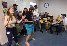 Program director Caitlin Sussman (left) joins in singing with the Voices of Hope choir at Friendship House, a mental health drop-in center in Morgantown, W.Va. Photo by Mike DuBose, UMNS.