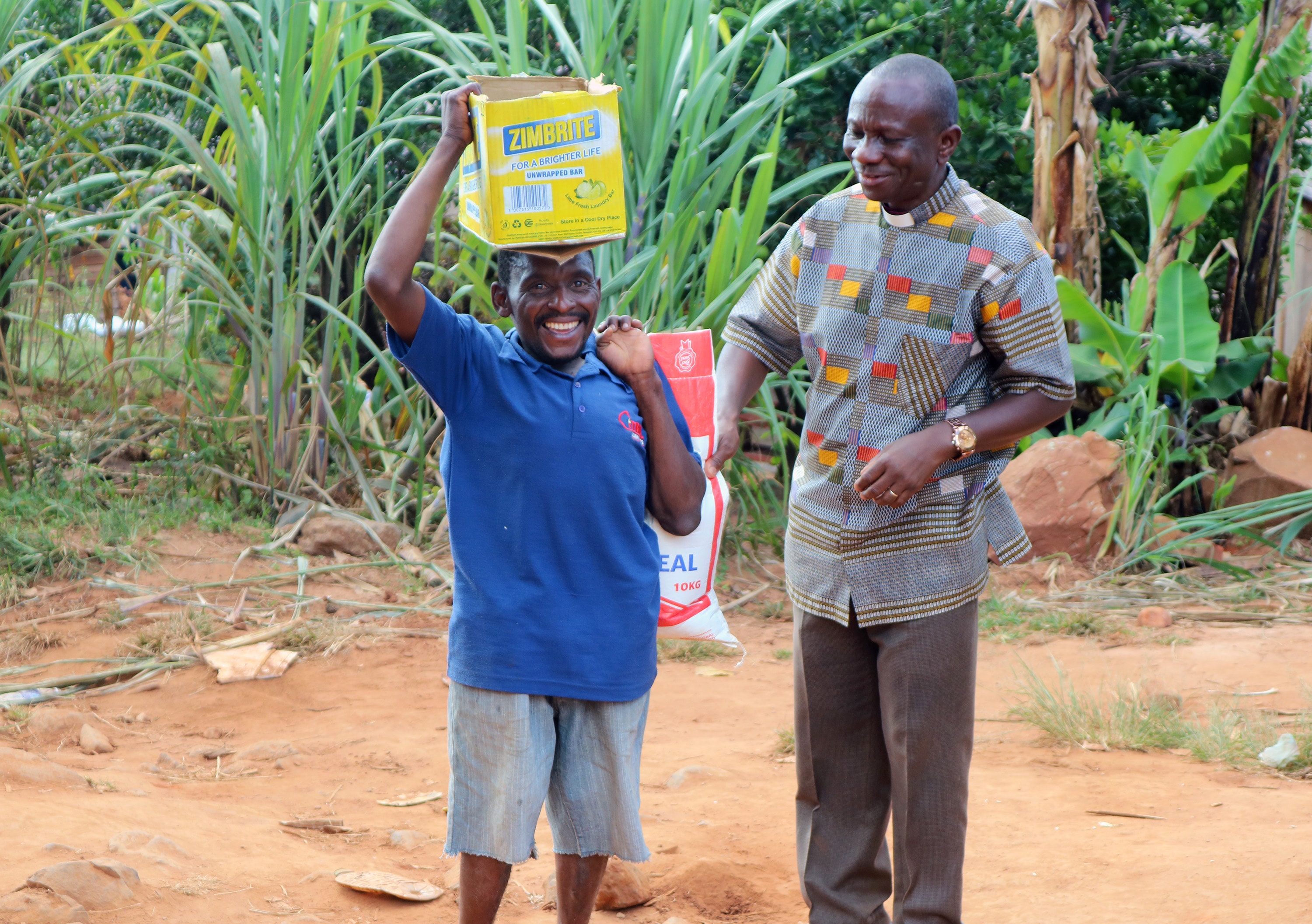 Gondayi Gokosho, left, receives supplies from The United Methodist Church in Zimbabwe. The Rev. Alan Gurupira, right, administrative assistant to Bishop Eben K. Nhiwatiwa, was among the church leaders who visited the Ngangu United Methodist Church Circuit to distribute donations following Cyclone Idai. Photo by Priscilla Muzerengwa, UMNS.