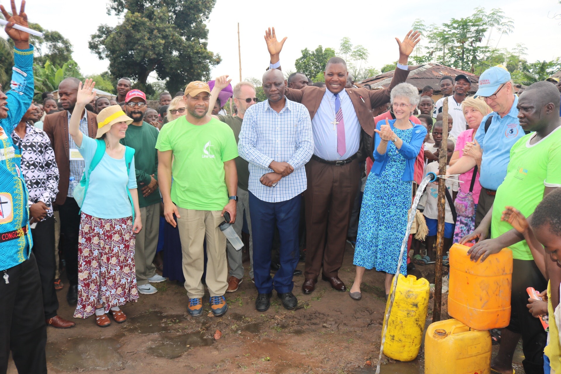 L’Evêque Daniel Lunge du Congo Central (en costume) et l’Evêque Peggy Johnson du Delaware (à sa gauche) se joignent à la population de Wembo-Nyama et du Delaware pour exprimer leur joie d’avoir de l’eau potable. La population de Wembo-Nyama a longtemps souffert des maladies dues à la mauvaise qualité de l’eau qu’elle consommait. Photo de François Omanyondo, UM News.