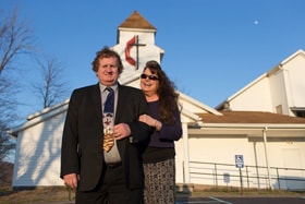 The Rev. Jamie Sprague and his wife, Kay, stand in front of Kanawha Chapel United Methodist Church in Davisville, W.Va., where Sprague serves as a licensed local pastor. Photo by Mike DuBose, UM News.