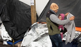 Jesús, a migrant from Michoacán state in Western Mexico, tries to shield his 1-year-old daughter, Kataleya, from a cold drizzle falling at the tent encampment where they are living at the foot of the Paso del Norte Bridge in Juárez, Mexico. Michoacán is among five states in Mexico given the highest-risk “do not travel” warning by the U.S. State Department. Photo by Mike DuBose, UM News. 