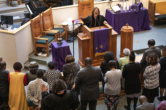 The Rev. Sheila Peters from Braden Memorial United Methodist Church preaches at the first Sunday service held at Gordon Memorial United Methodist Church following the March 3 tornado which heavily damaged Braden. Praying over attendees on the floor is the Rev. Paula B. Smith, pastor at Gordon Memorial. Photo by Kathleen Barry, UM News.