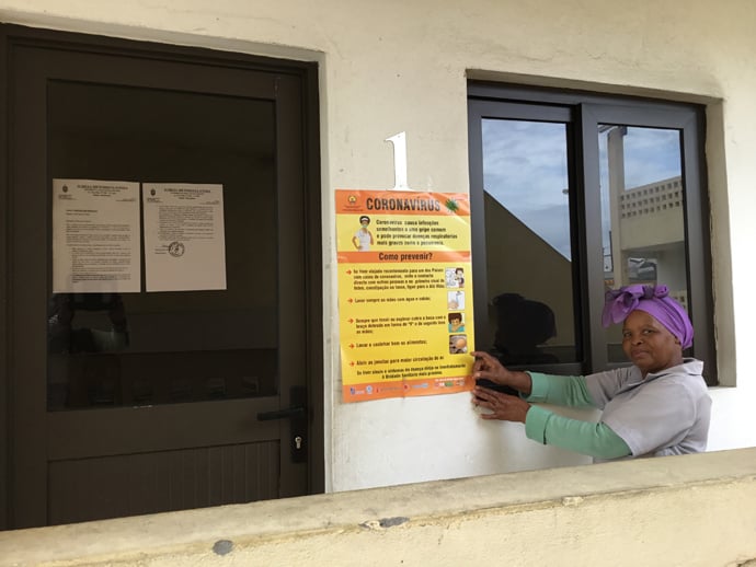 Rita Samuel aponta para o cartaz e o comunicado episcopal que falam das medidas a serem tomadas face ao COVID-19. Foto de João Filimone Sambo.