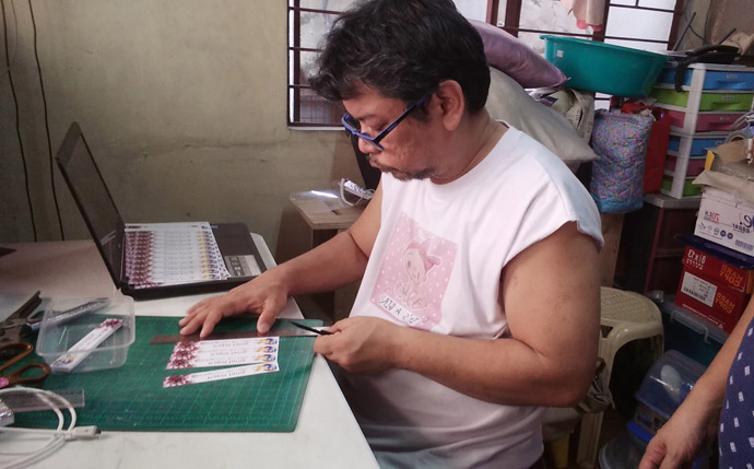 Melvin Nor S. Ramos, a layperson from Kawan ni Kristo United Methodist Church in the South Bulacan District of the Philippines, works on labels for his DIY face shields. Together with his family and other church members, he pooled resources to create the needed protection for local hospitals and health centers in the fight against the coronavirus. Photo courtesy of Melvin Nor S. Ramos.