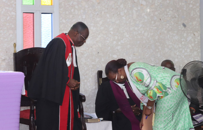 Côte d'Ivoire Bishop Benjamin Boni and Lydie Acquah, director of the Voice of Hope radio station, greet each other while avoiding shaking hands during the closing worship service of the radio's 10-year anniversary celebration March 15. The church is reinforcing measures to curb the spread of COVID-19. Photo by Isaac Broune, UM News.