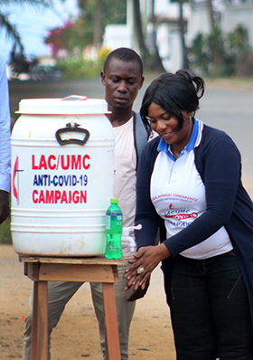 Lango W. Toe, director of health for The United Methodist Church in Liberia, demonstrates hand-washing at one of the stations set up along the streets in Sinkor, Liberia. Photo by E Julu Swen, UM News.