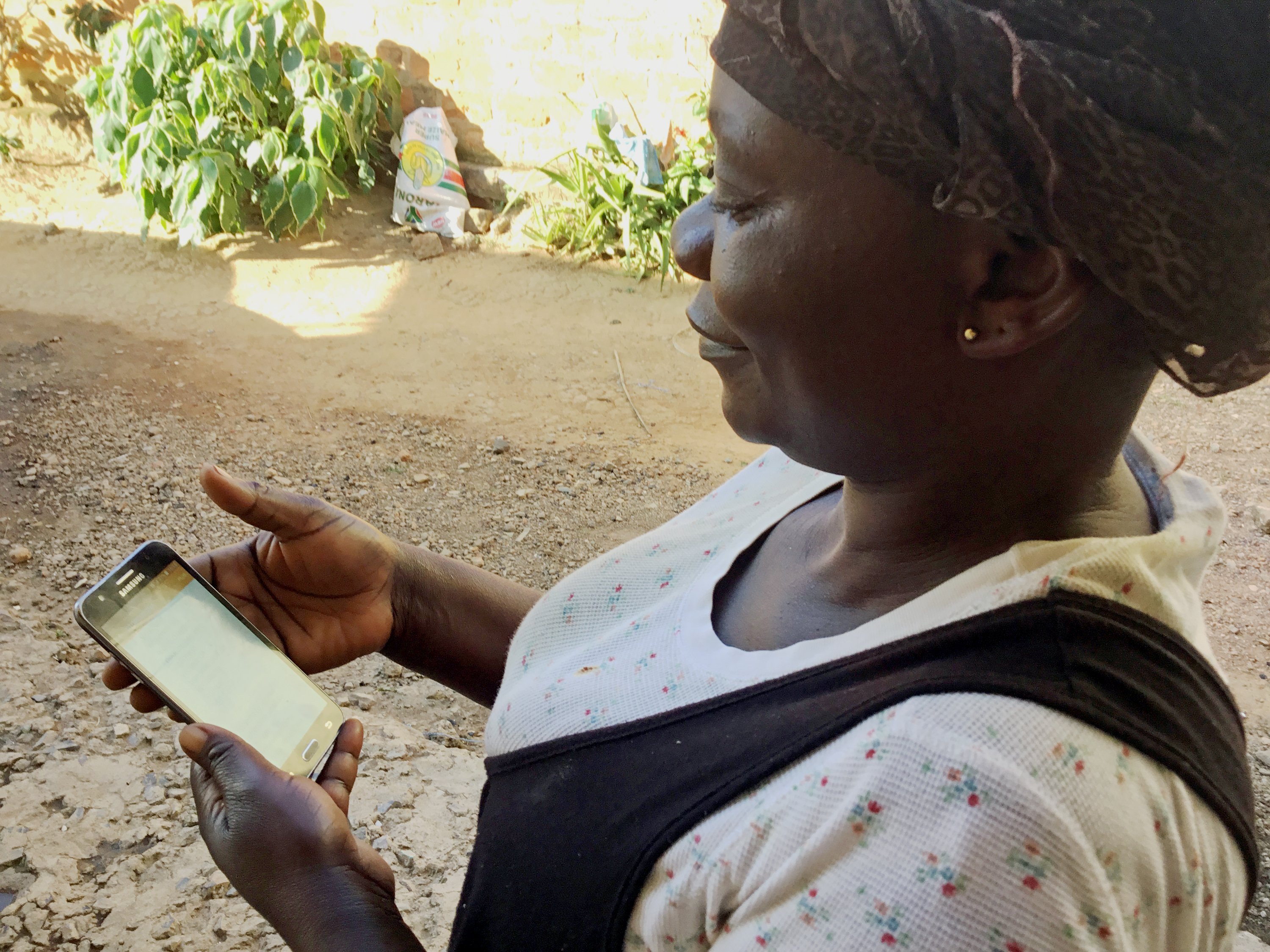 Nathalie Kabulo lit un message de prévention sur son portable. En Tanganyika et au Nord Katanga, peu de femmes ont accès à un téléphone portable. Photo de Betty Musau, UM News.