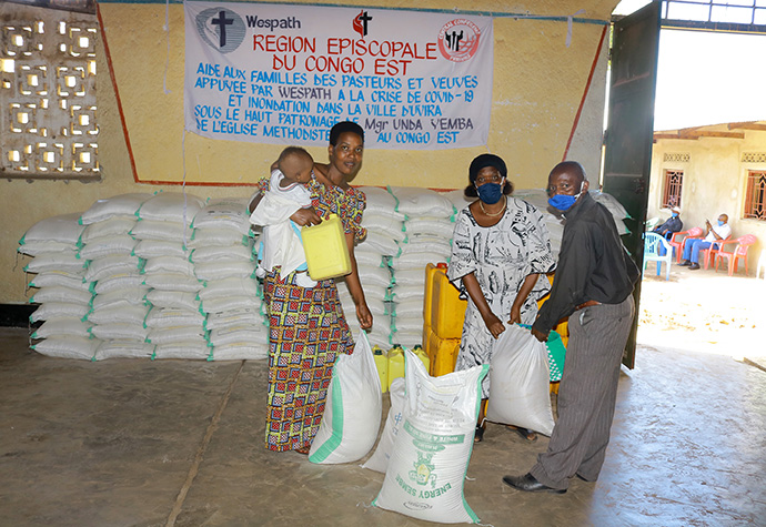 The Rev. Simon Kombi Ramazani (right), connectional ministry director for the Kivu Conference, gives food to a widow whose husband died following flooding in Uvira in April. Wespath Benefits and Investments, the United Methodist pension agency, provided food relief to pastors and widows in the Uvira District. Photo by Philippe Kituka Lolonga, UM News.