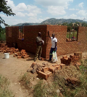 The home of Elizabeth Hwatira was greatly damaged by Cyclone Idai. Here engineer, Cassian Mutsambiwa, and builder Pamganai Ziwewe, stand before the Hwatira home in Ward 20, Chirorwe, Bikita, Masvingo. Photo by Chenayi Kumuterera, UM News. 