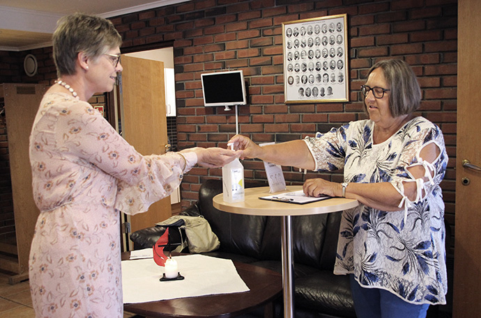 Elizabeth Moe Skreosen, chairwoman of The United Methodist Church Porsgrunn in Norway, is welcomed by fellow church member Kari Palmgren with an offer of hand sanitizer. Photo courtesy of The United Methodist Church Porsgrunn.