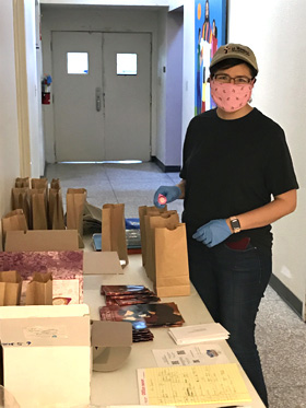 The Rev. Raquel Feagins of La Trinidad United Methodist Church in San Antonio prepares bags that include the Upper Room devotions and communion elements for about 220 people. People pick up the packages curbside during the time of online worship. Photo by the Rev. John Feagins of La Trinidad United Methodist Church.