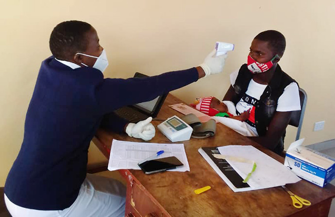 Belinda Mashoko, sister in charge at United Methodist Dindi Clinic, scans Benhilda Pfupa's forehead with an infrared thermometer at the mission hospital in Uzumba Maramba Pfungwe, Zimbabwe. The no-touch thermometers were part of a donation from the Zimbabwe Council of Churches, an ecumenical group that includes The United Methodist Church. Photo by Kudzai Chingwe, UM News.