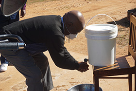 Naboth Makunike, the building committee chairperson for Mutasa Central United Methodist Church of Mutasa Nyanga District, washes his hands from a 20-liter bucket of sanitized water at a church gathering at Ehnes Memorial United Methodist Church. Photo by Kudzai Chingwe, UM News.