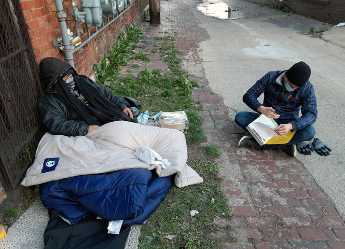 Outreach worker Zach Betthauser (right) of Cass Community Social Services in Detroit visits with an unidentified homeless man. Photo by Justin Alesna.